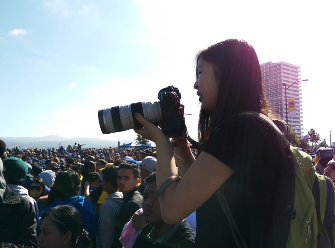 Mosaic staff photographer Rachel Lee gets situated in the crowd to photograph the team. // Photo by Robert Salonga